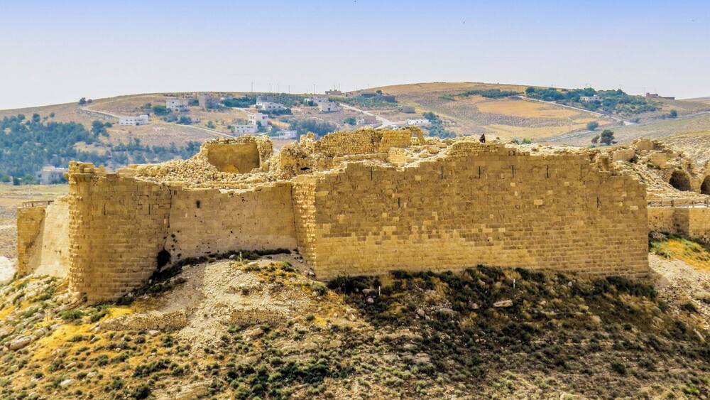 Eine historische Steinburg mit Ruinen und einer hügeligen Landschaft im Hintergrund.