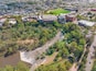 Aerial view of a river and waterfall bordered by city buildings along side and bush