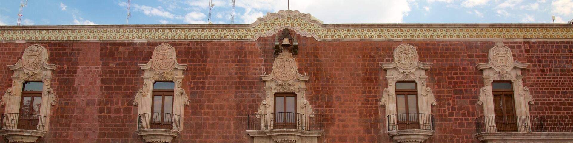 A historic building with ornate balconies, large wooden doors, and a decorative cornice.