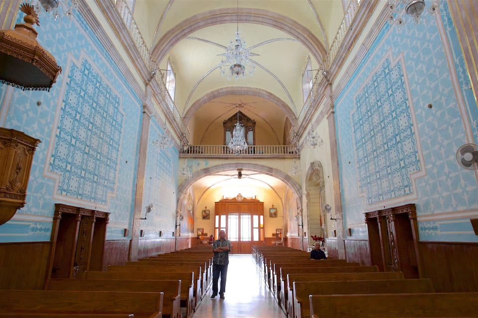 Interior d'una església ornamentada amb parets de colors blaves i motius, pews de fusta i un altar central.