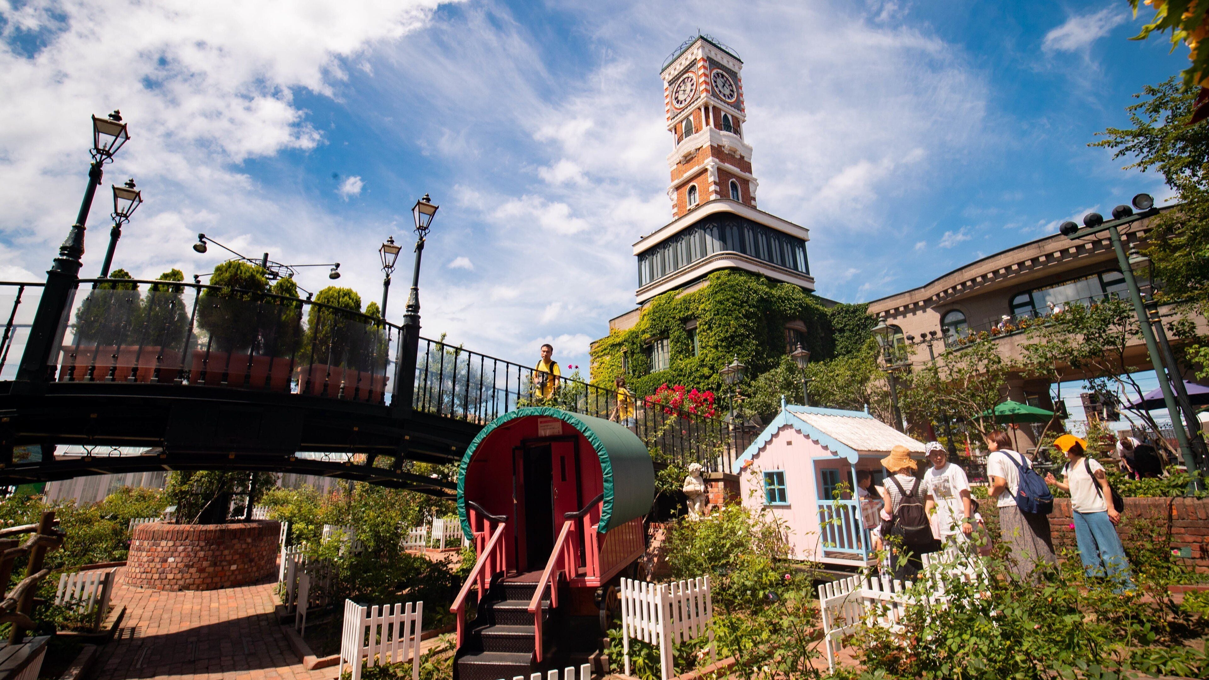 Um parque com uma ponte, uma torre e uma pequena casa.