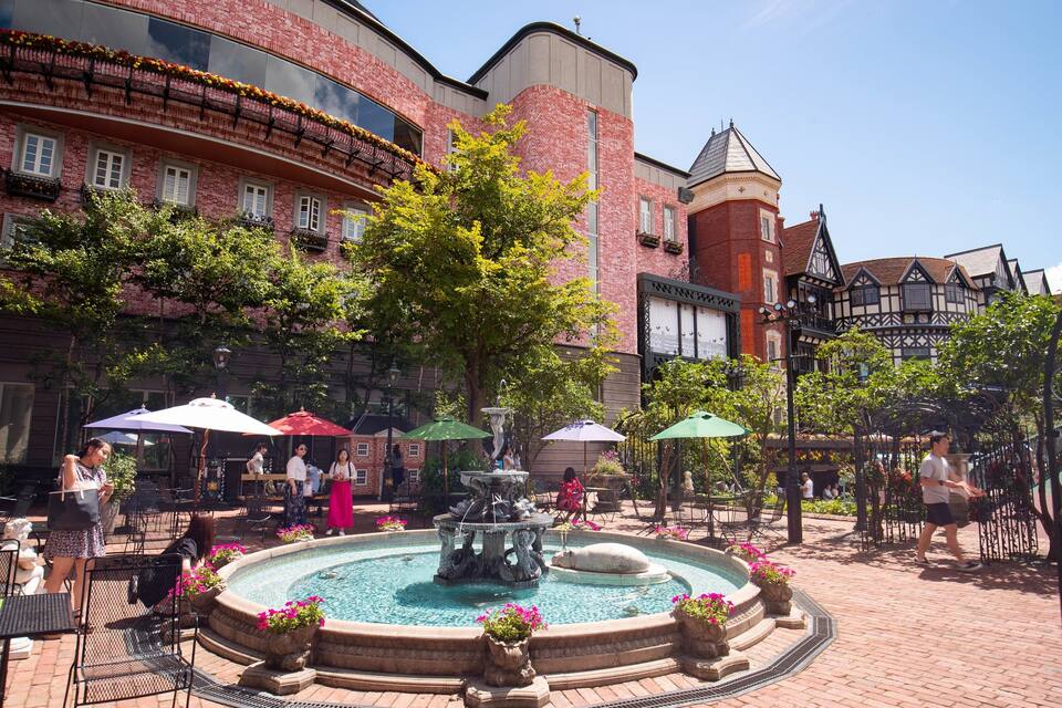 A courtyard with a fountain, outdoor seating, and historic buildings.