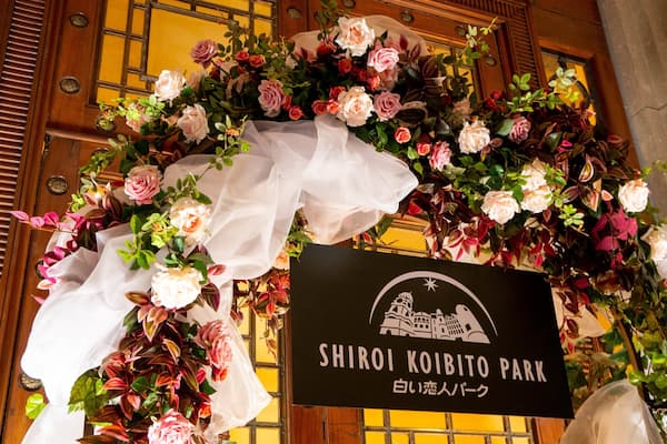 A sign for Shiroi Koibito Park with a floral arrangement above it.