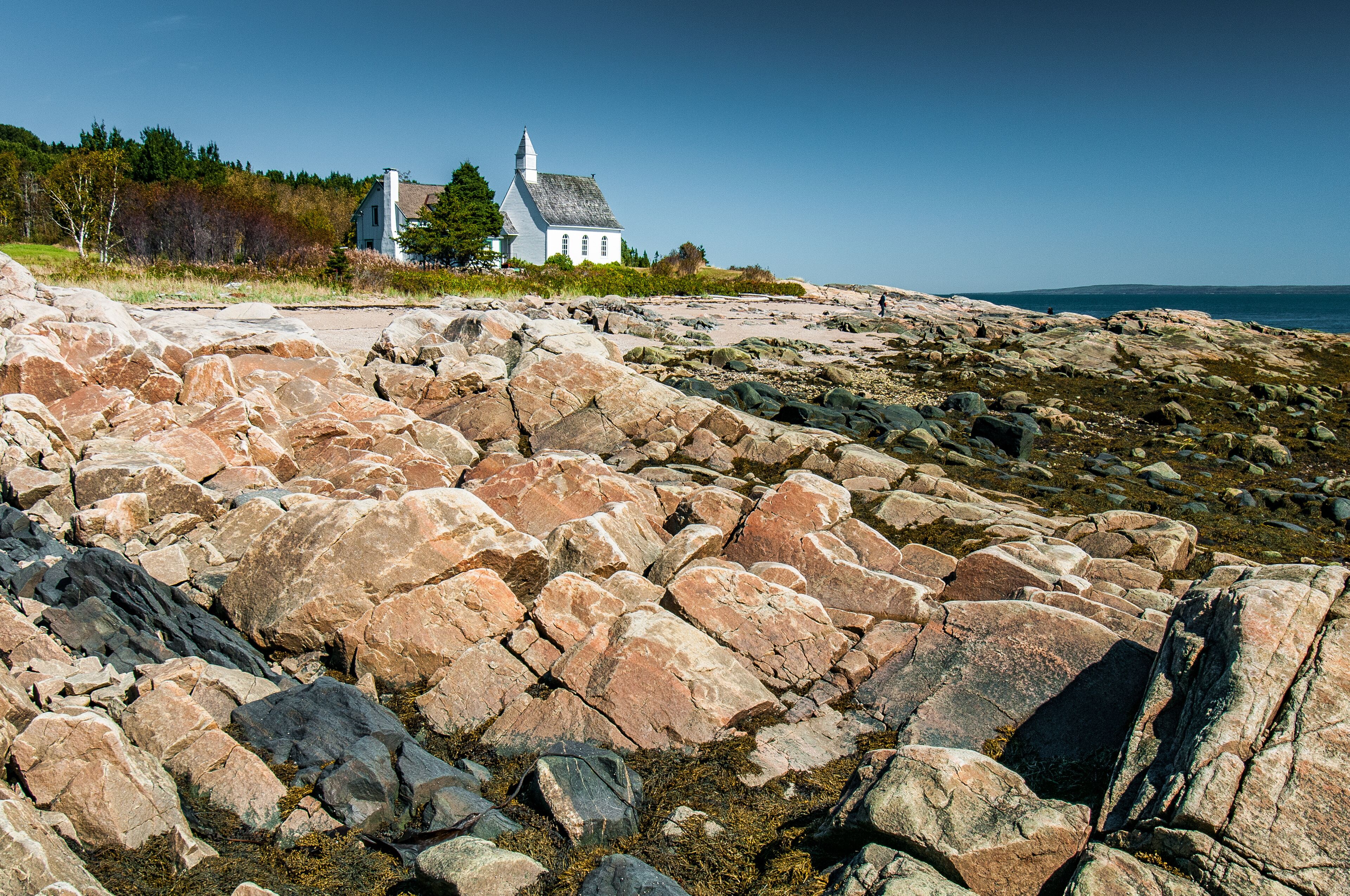 The small church of Port-au-Persil behind the rocks at low tide, Québec, Canada