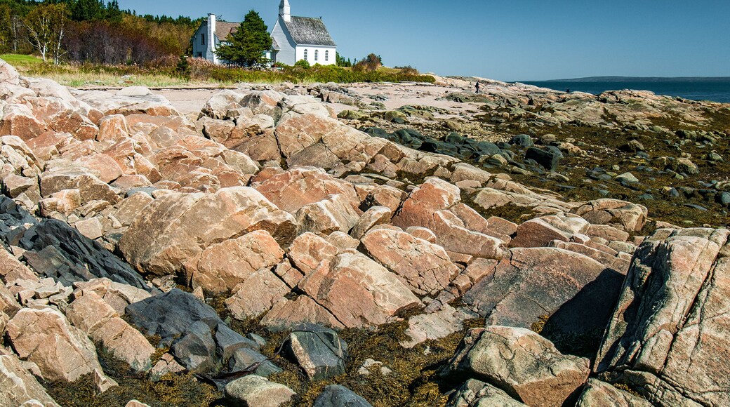 The small church of Port-au-Persil behind the rocks at low tide, Québec, Canada
