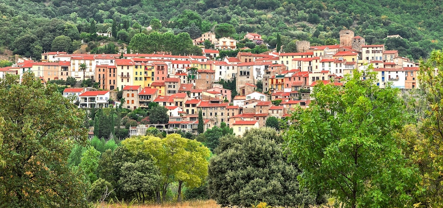 A hillside village with colorful buildings and dense greenery.