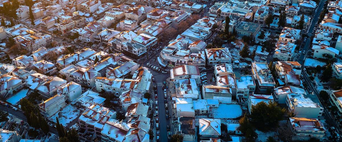 An aerial view of a snow-covered town with dense housing and a mountain in the background.