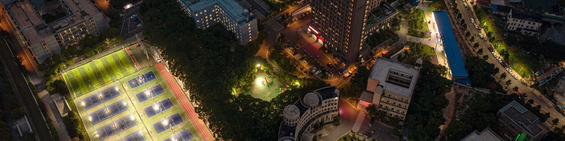Night view of the dormitory area of a university in China, with lights on the small tennis court