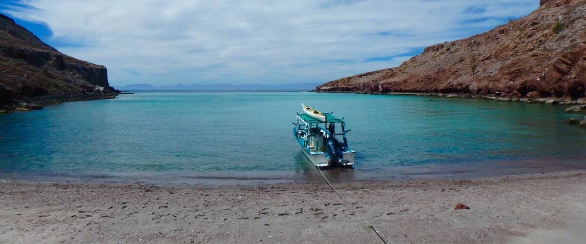 A kayak tied to a dock on a calm turquoise lake surrounded by rocky cliffs.