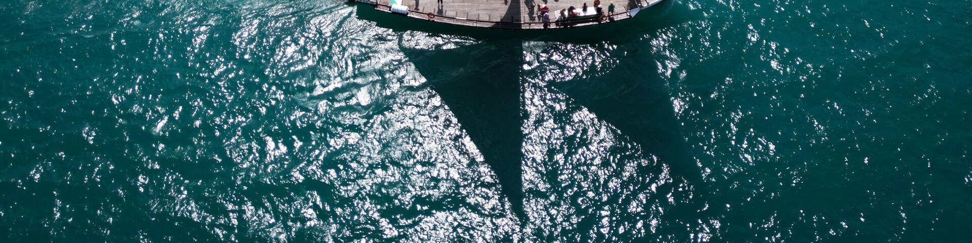 Yvoire, France - 27 July 2024: Aerial view of a traditional sailing boat cutting through the turquoise waters of Lake Geneva, sails billowing in the wind, reflecting the sunlight.