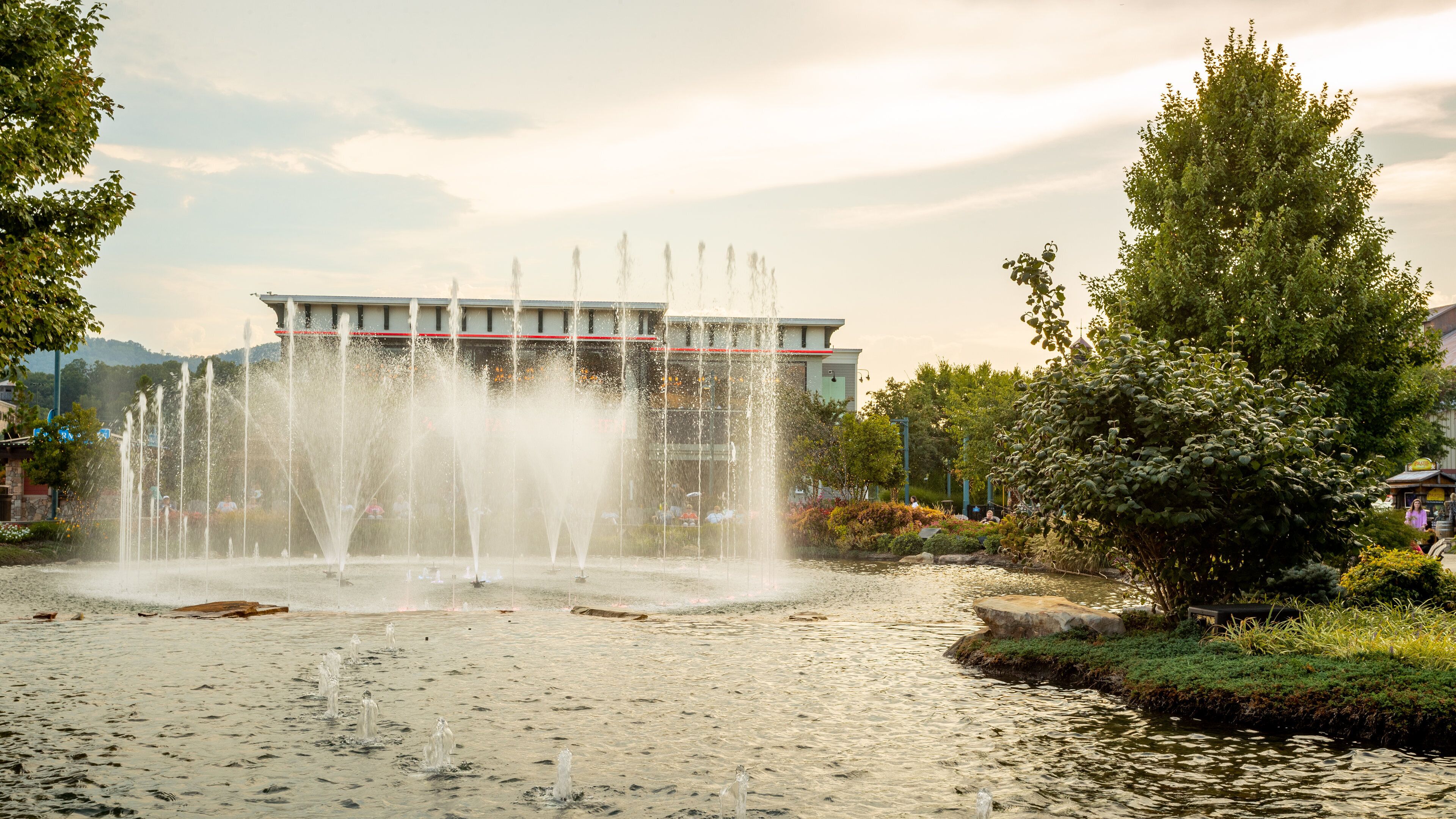 Island at Pigeon Forge showing a fountain, a pond and a sunset