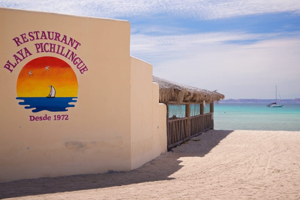 A beach with a sign for Restaurant Playa Pichilingue.