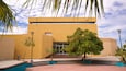 A building with a yellow facade, a tree in front, and a clear sky.