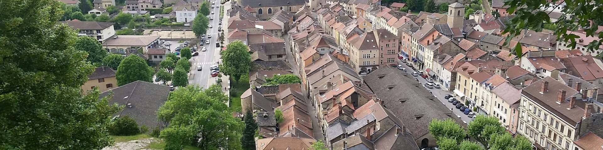 Un pueblo con edificios históricos, una calle principal y zonas verdes circundantes.
