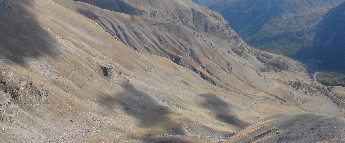 Een bergachtig landschap met ruig terrein en verre bergtoppen onder een heldere lucht.