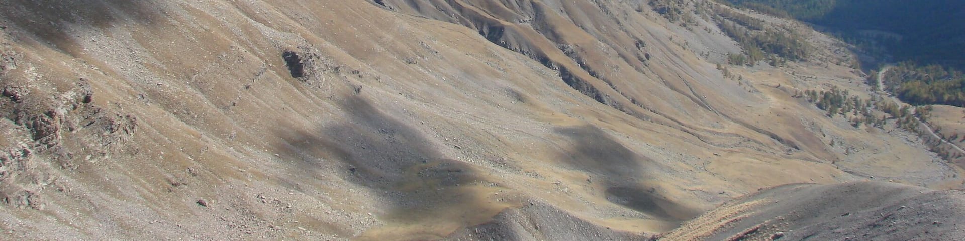 A mountainous landscape with rugged terrain and distant peaks under a clear sky.