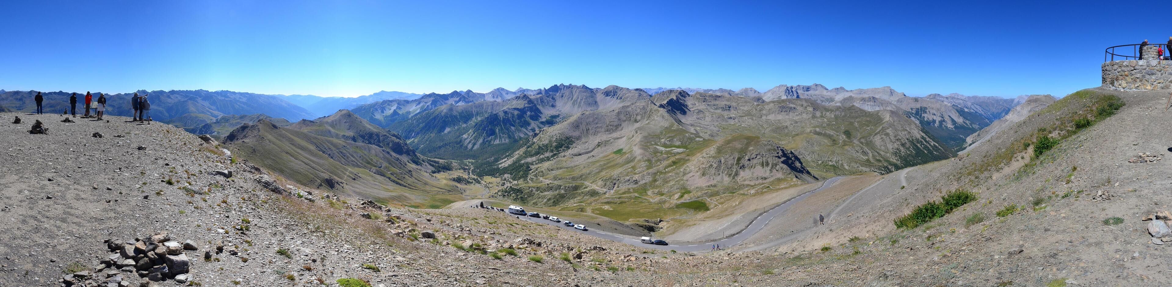 A mountainous landscape with a winding road and a stone viewing platform.