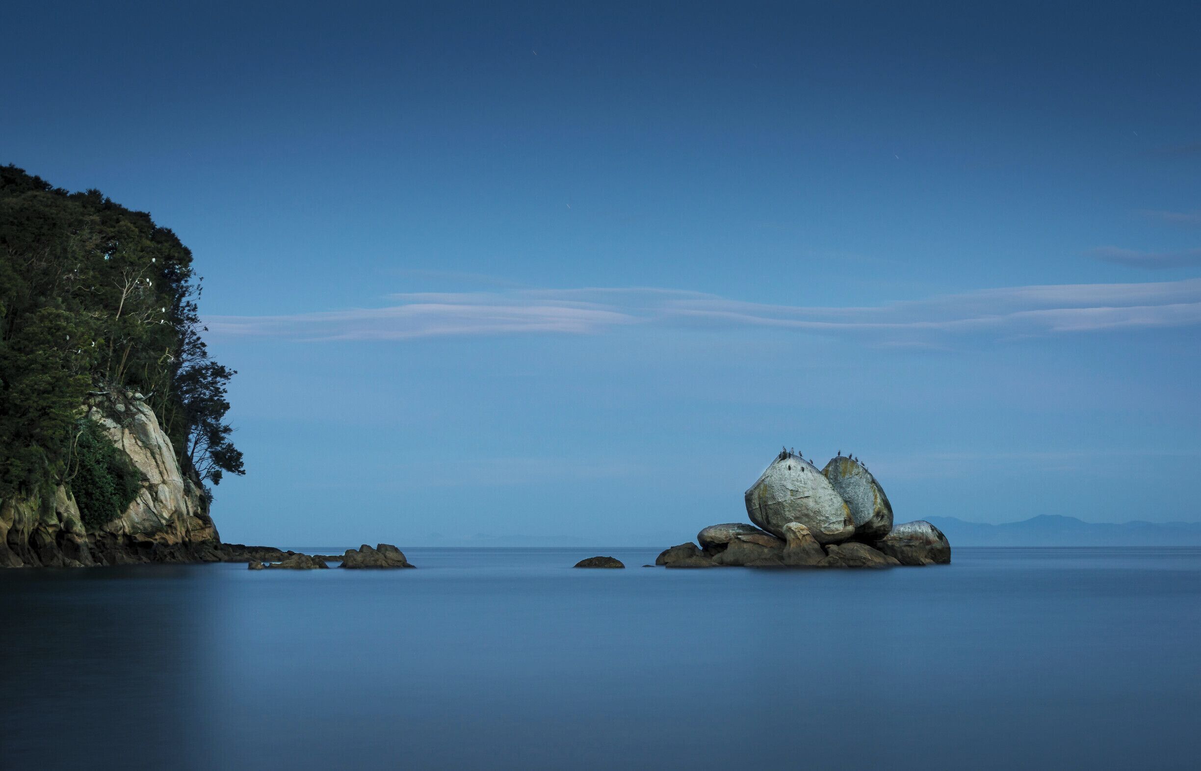 This is a (short) long exposure shot of Split Apple Rock, which is located just south of the Abel Tasman National Park, between Kaiteretere and Marahau.  After a 10 minutes walk down through some bush you come out to a long stretch of deserted golden sand, with the unmistakable Split Apple Rock sitting just off shore.

We arrived just after sunset (which meant it was dark when had to walk back up through the bush!) to a incoming tide and a calm sea.  If you look closely you can see that the rock is used as a perch for the local Shag's (Cormorants), and there are a few perching in the trees as well.
