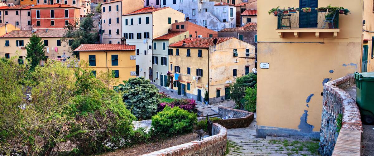 A cobblestone street in a historic town with colorful buildings and a stone wall.