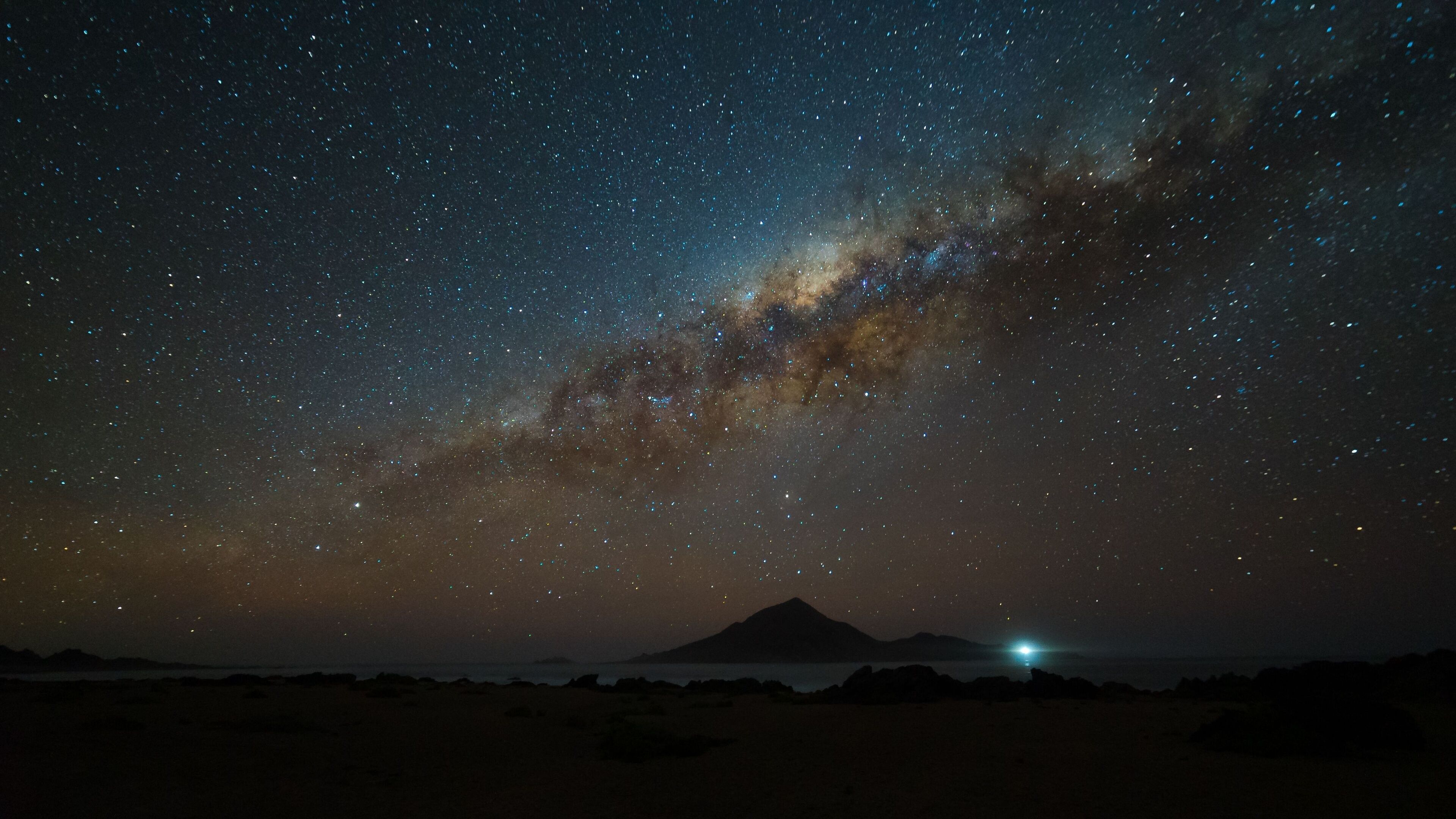 A starry night sky over a mountainous landscape.