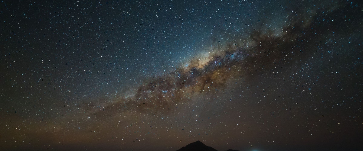 A starry night sky over a mountainous landscape.
