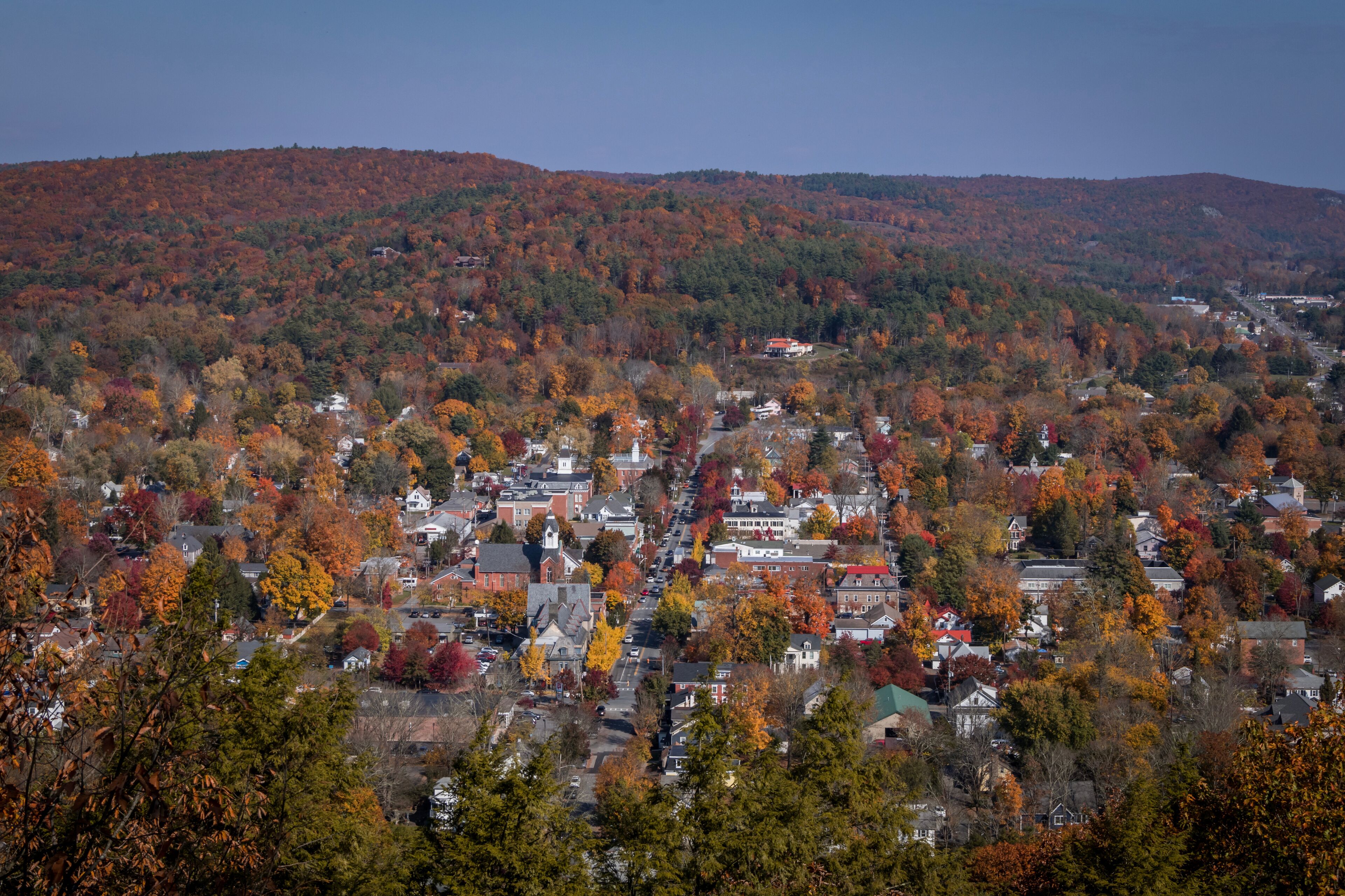 A town surrounded by autumn-colored trees and hills.