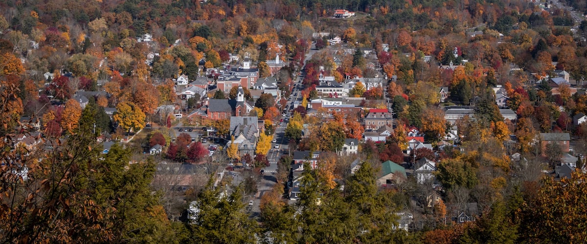 A town surrounded by autumn-colored trees and hills.