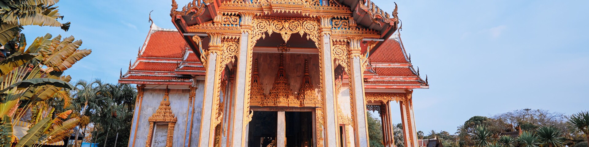 Un templo de arquitectura ornamentada, una mujer con un vestido amarillo y un cielo azul despejado.