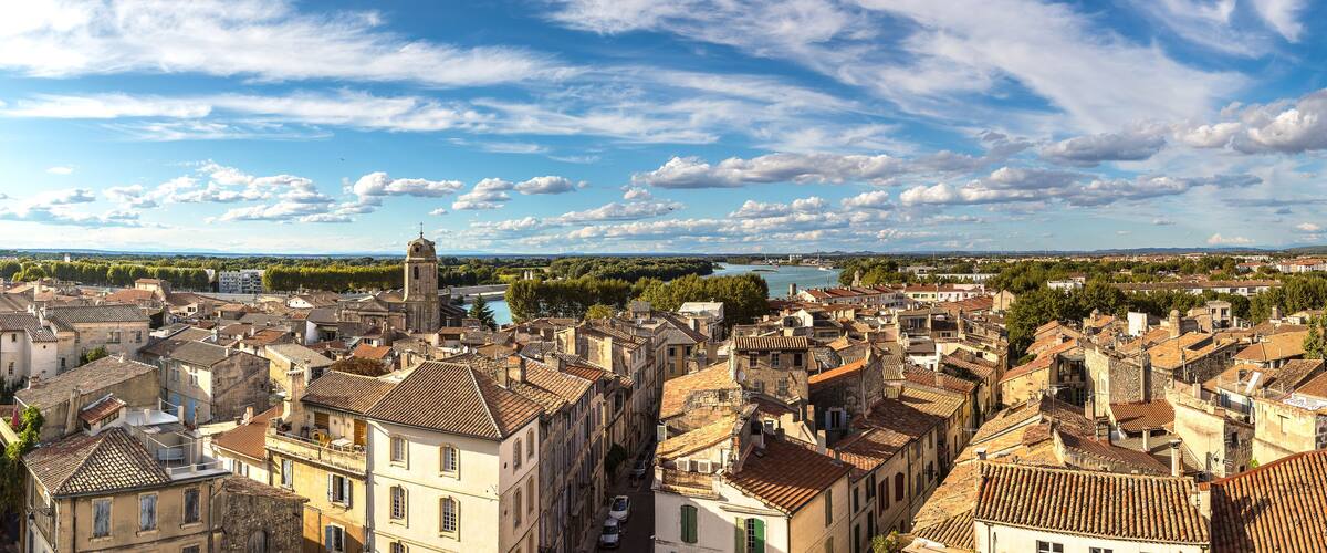 A historic town with a prominent church tower, dense buildings, and a river in the background.