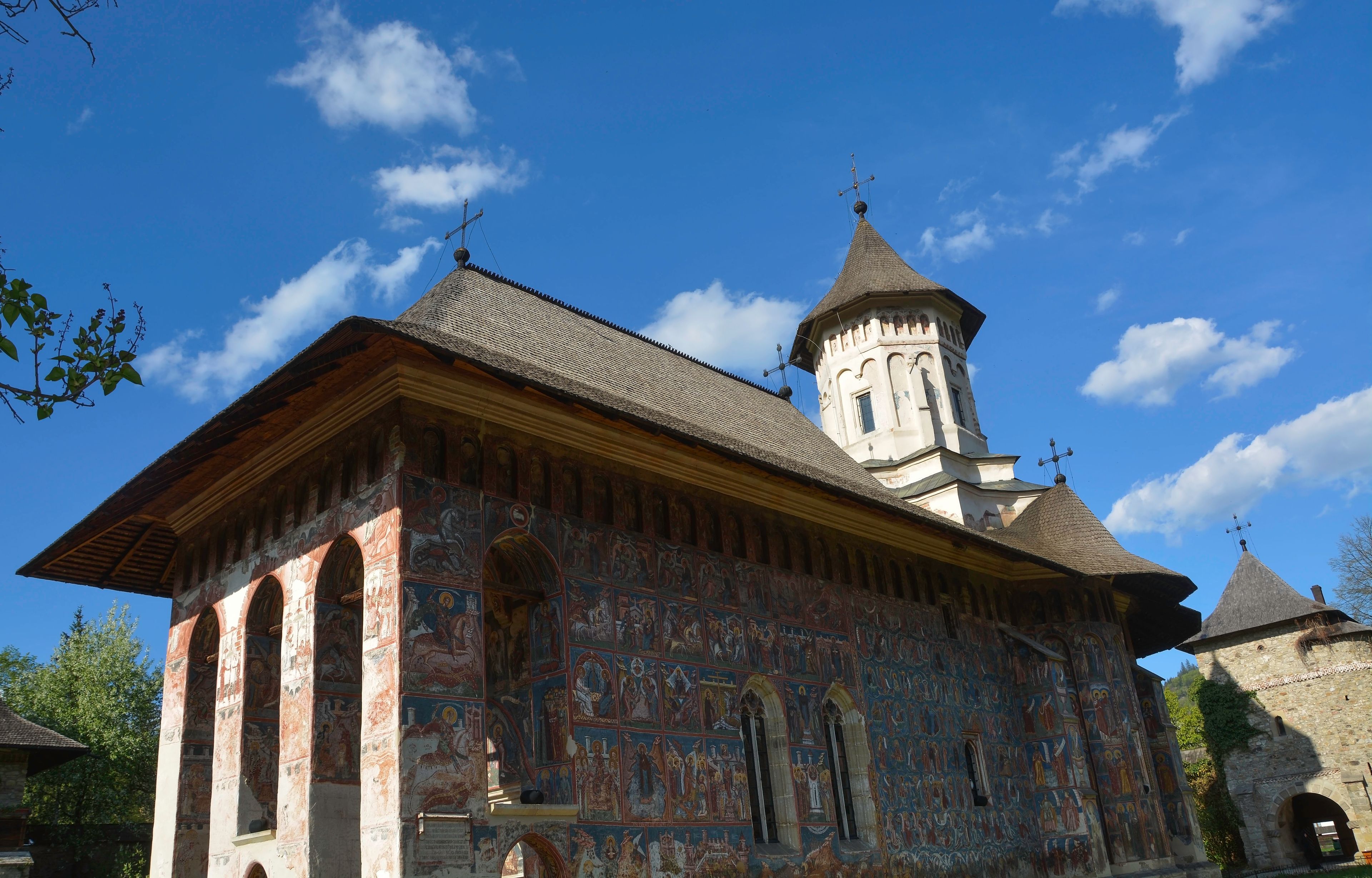Una iglesia histórica con un campanario, frescos detallados y un cielo azul despejado.