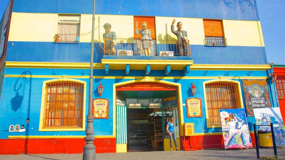 Ein buntes Gebäude mit einer blauen und gelben Fassade, einem Balkon mit Statuen und einem Schaufenster mit verschiedenen Schildern.