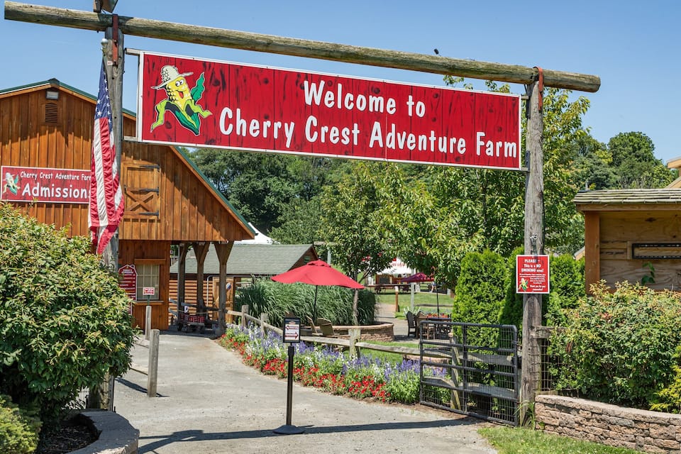 En byggnad av trä med en skylt där det står: ”Välkommen till Cherry Crests äventyrsgård”.
