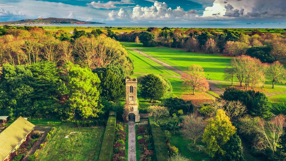 Aerial view over the St. Anne Park, revealing the old tower and the Howth peninsula on the horizon. Autumn Irish landscape in November.