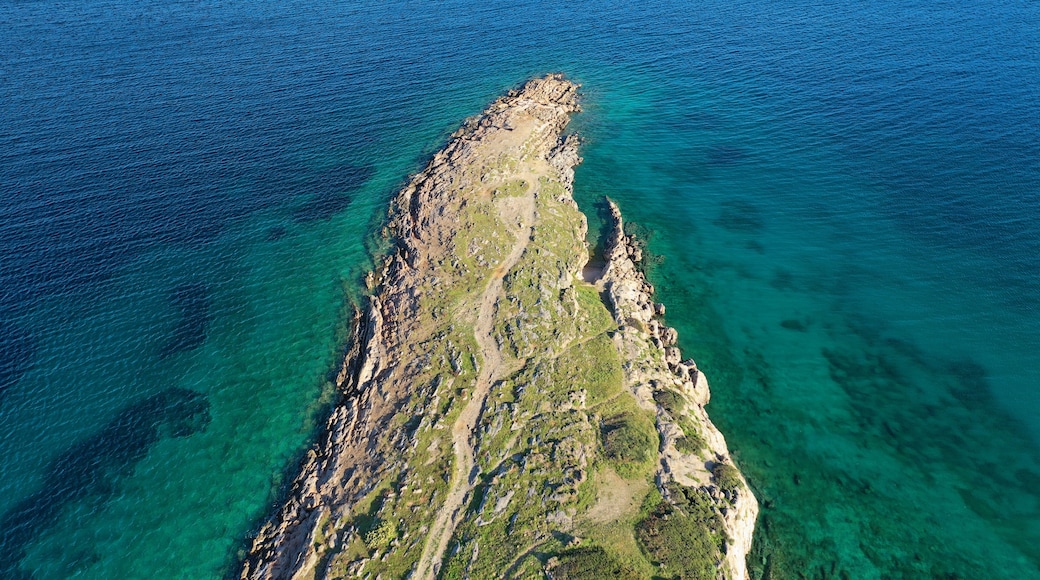 An aerial view of a rugged coastline with clear blue waters and rocky terrain.