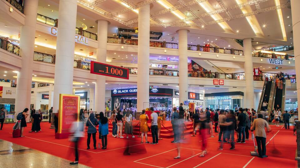 A multi-level shopping mall with a prominent red carpet event area, escalators, and various retail stores including a Samsung store.