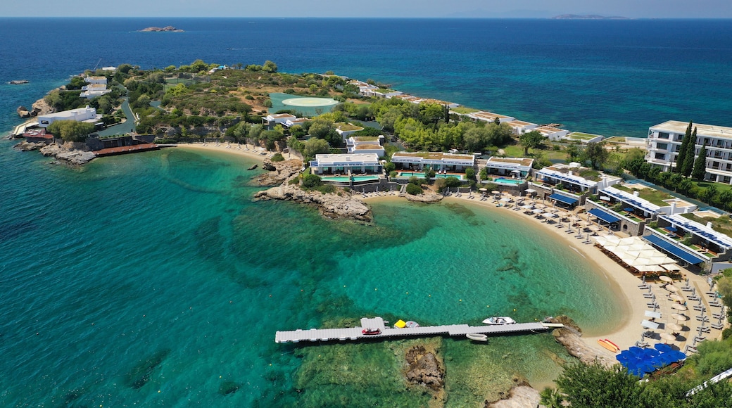 A coastal resort with clear turquoise waters, a sandy beach, and modern buildings with green roofs.
