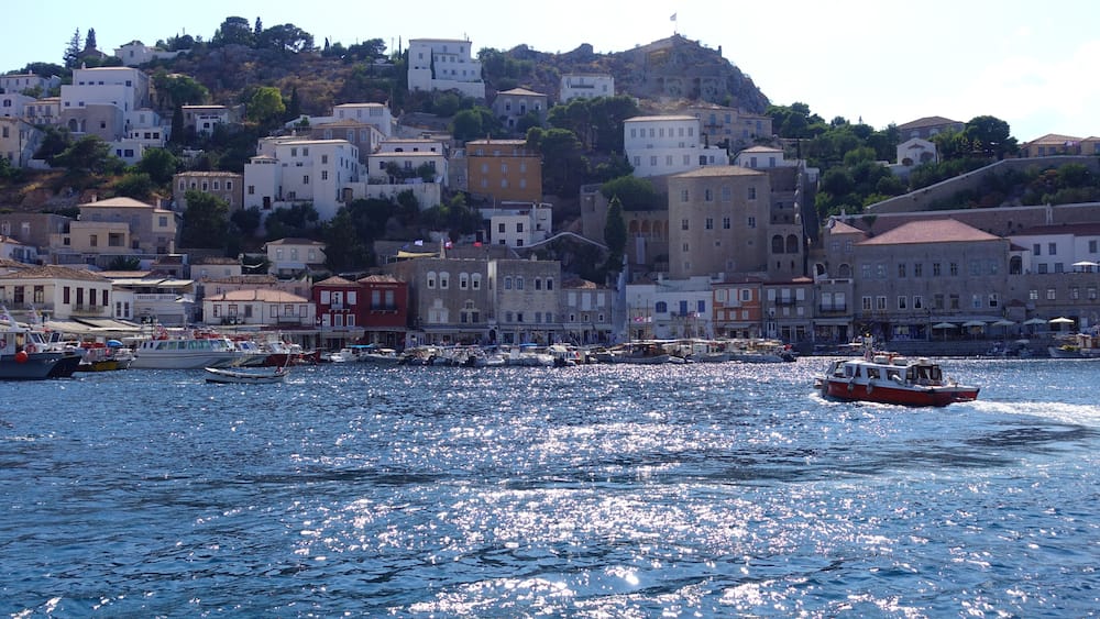 A coastal town with buildings on a hillside, boats on the water, and a clear sky.