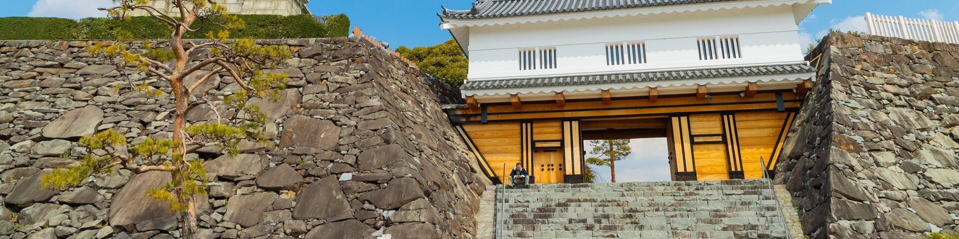 A traditional Japanese building with a stone staircase and a stone monument in the background.