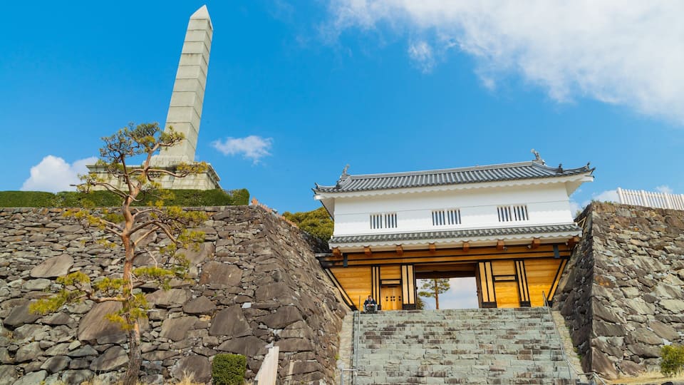 Un bâtiment traditionnel japonais avec un escalier en pierre et un monument de pierre en arrière-plan.