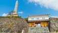 A traditional Japanese building with a stone staircase and a stone monument in the background.