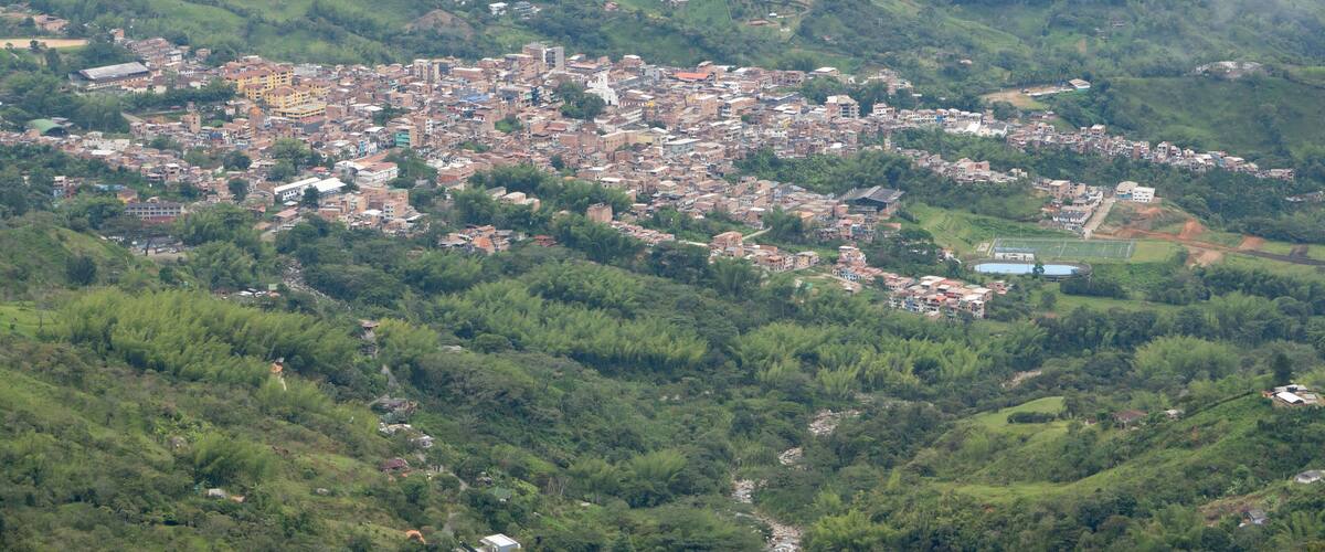 A town nestled in a valley surrounded by lush green hills.