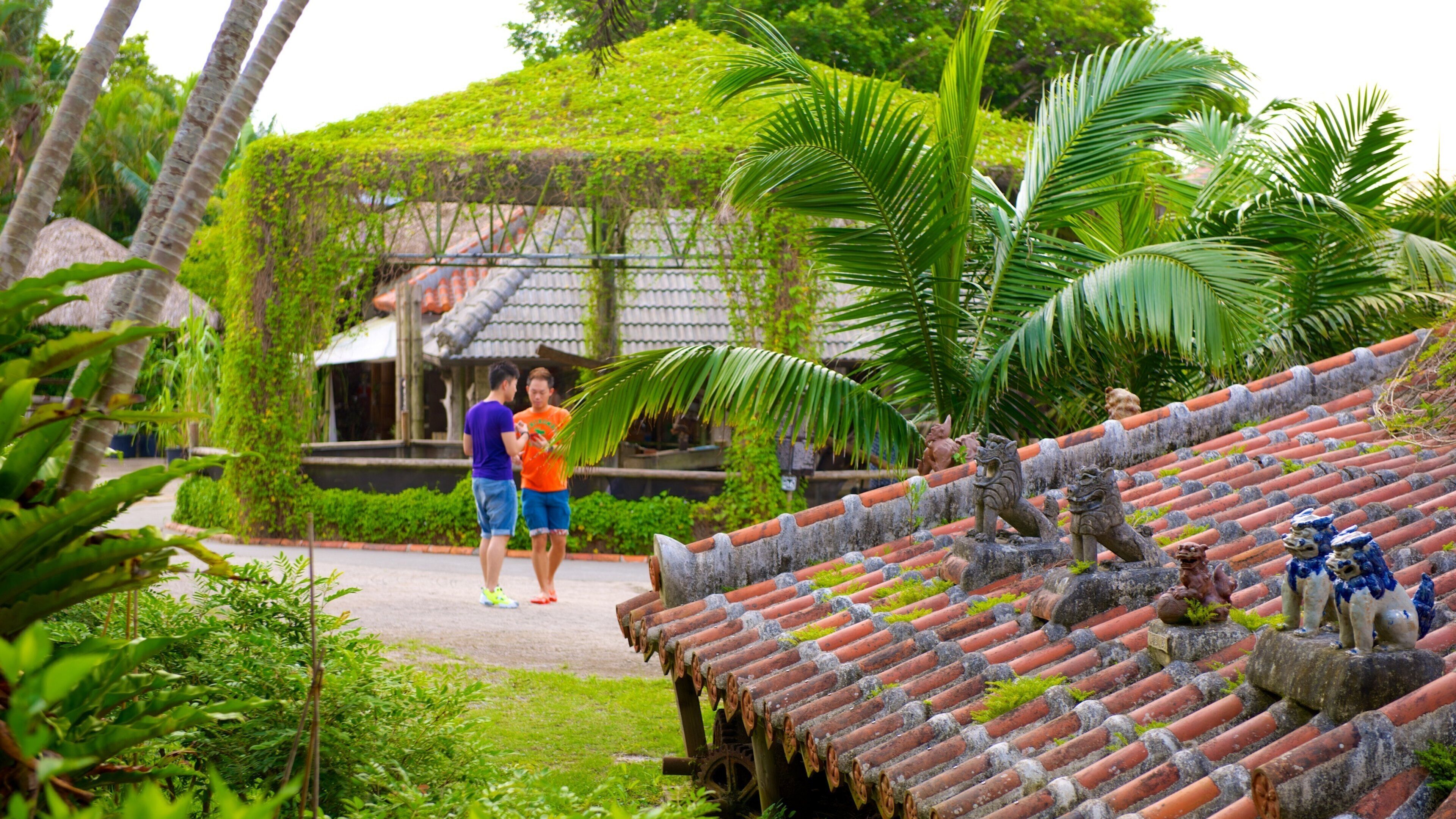 A traditional tiled roof with decorative lion statues, lush greenery, and a stone pathway.