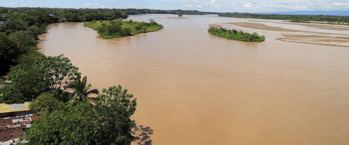 A wide river with multiple islands, surrounded by greenery and a partly cloudy sky.