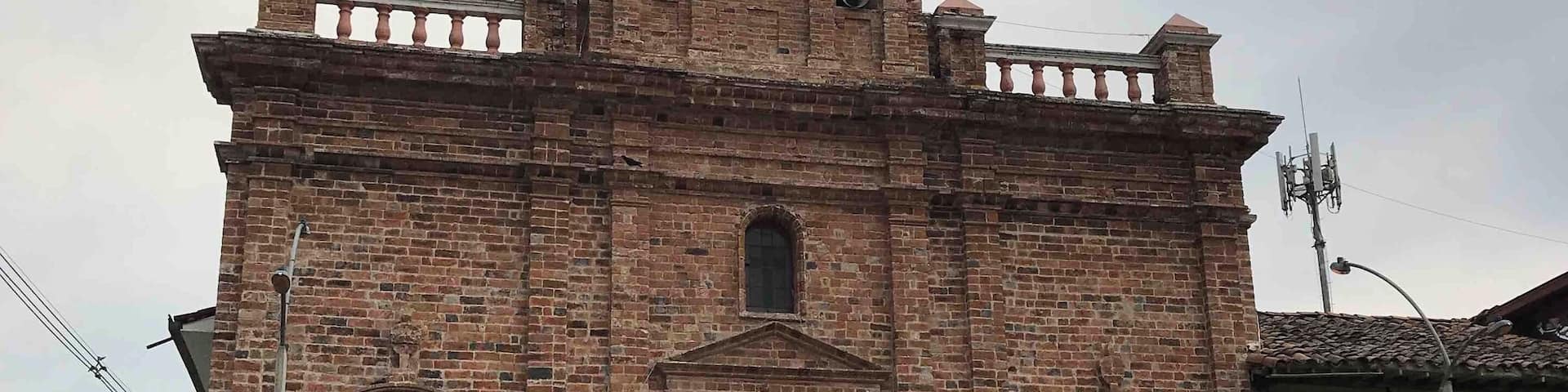 A historic church with a clock tower, arched windows, and a bell.