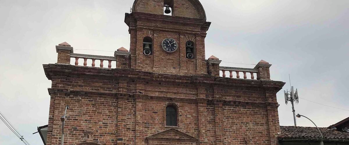 A historic church with a clock tower, arched windows, and a bell.