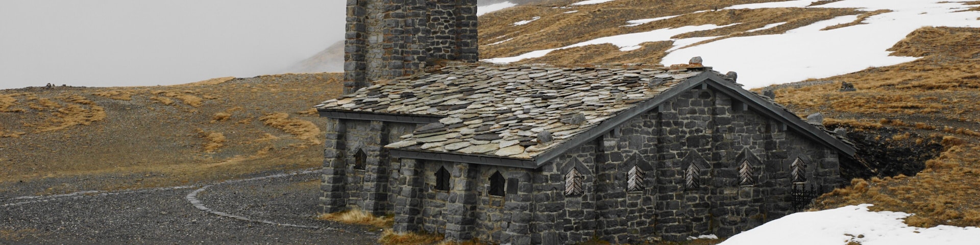 Una iglesia de piedra con un campanario y un paisaje nevado.