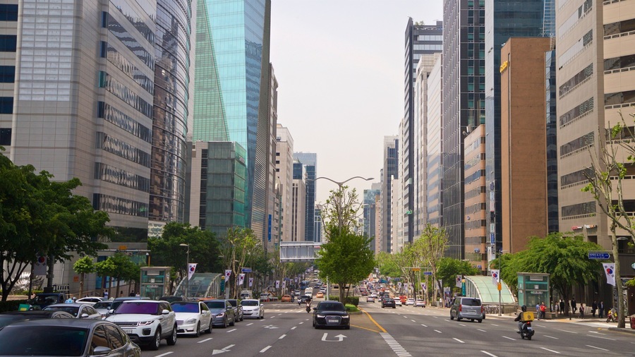 A busy urban street lined with modern high-rise buildings and cars.