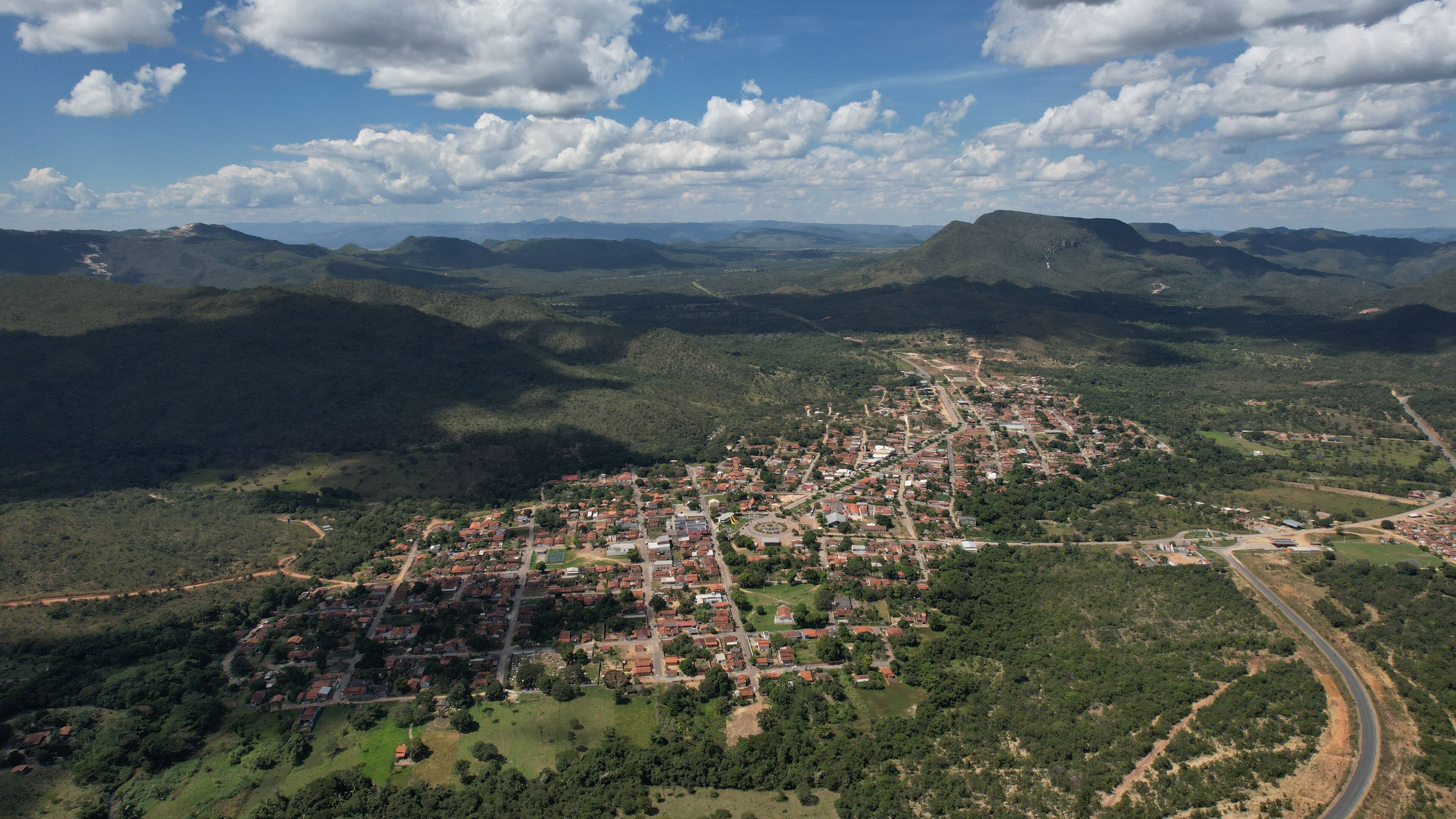 An aerial view of a town surrounded by mountains and greenery.