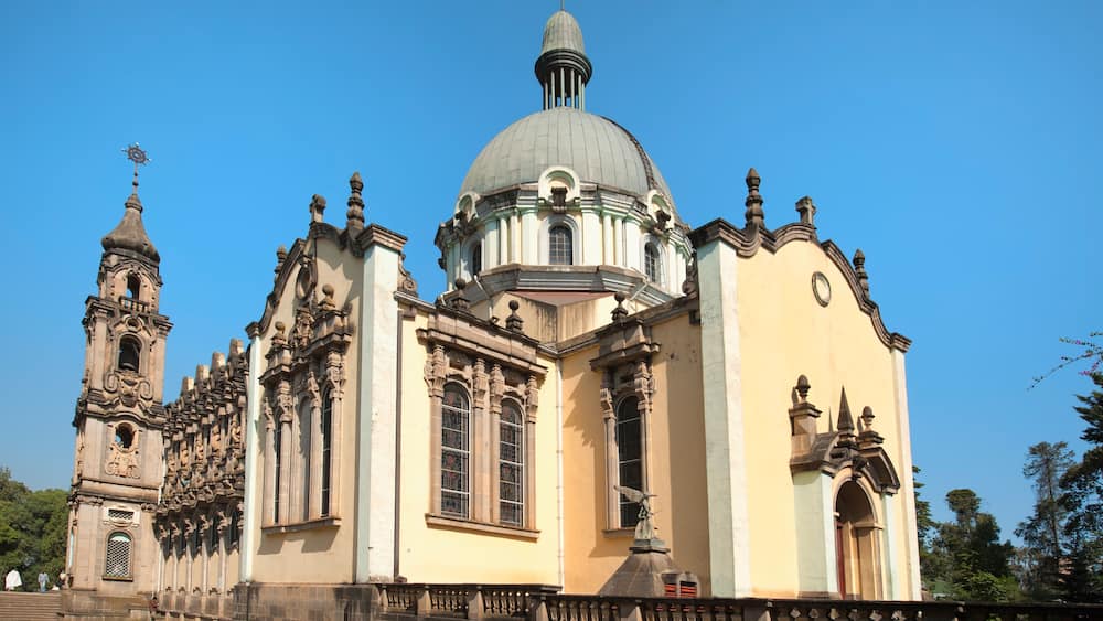 Eine historische Kirche mit einer großen Kuppel, aufwendigen Säulen und einem Glockenturm.