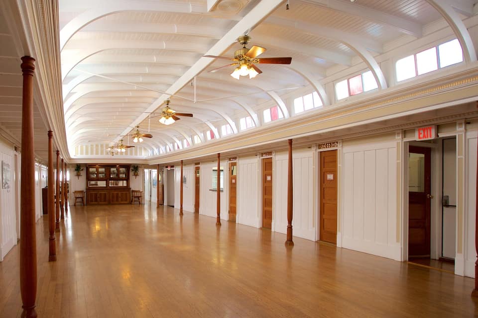A spacious hall with wooden floors, white walls, and a high ceiling with arched windows.